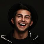 Portrait of a laughing young man in a black hat and jacket